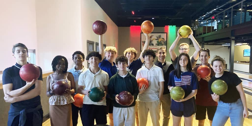 group of smiling teenagers in a bowling alley