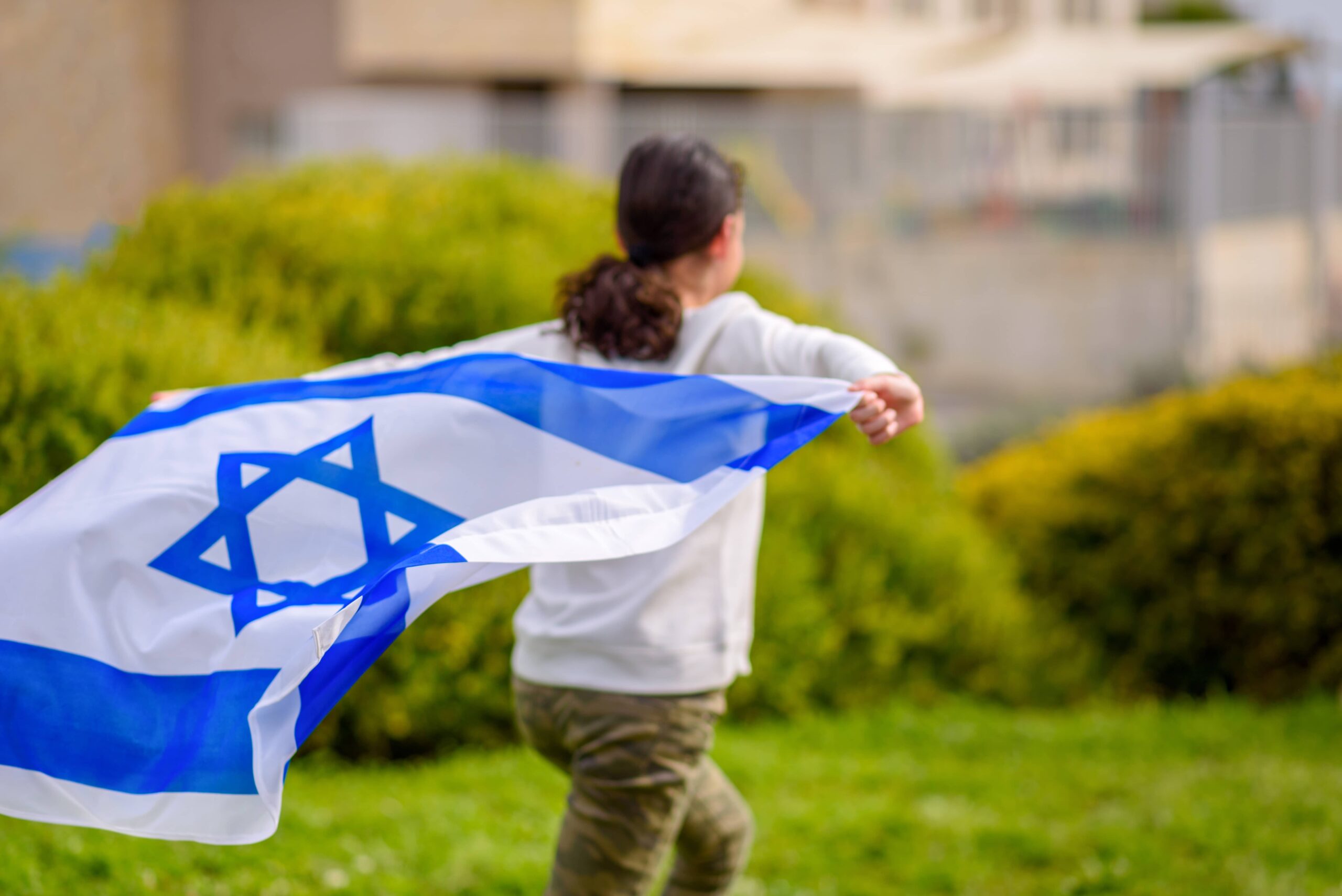 teenage child running with Israeli flag